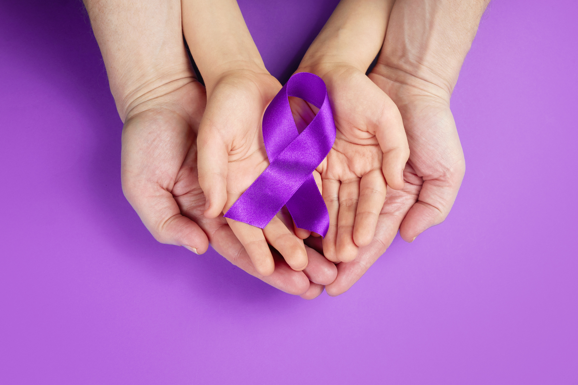 Hands Holding Purple Ribbon on Purple Background